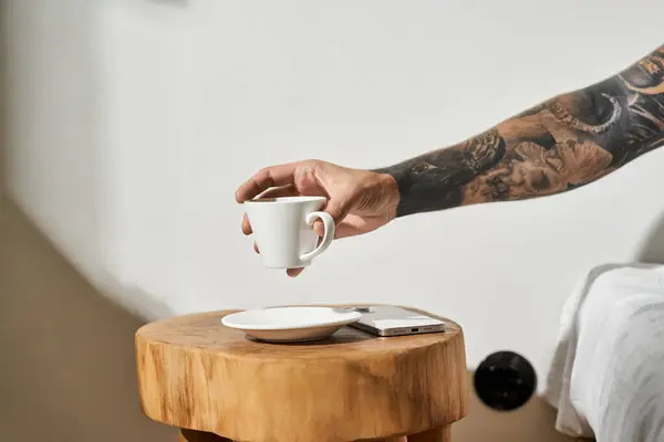 A young man with tattoos holding his coffee at home, surrounded by a relaxed atmosphere. — Stock Photo