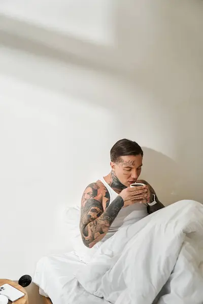 A handsome young man savors a warm beverage, embracing the tranquility of his home. — Stock Photo