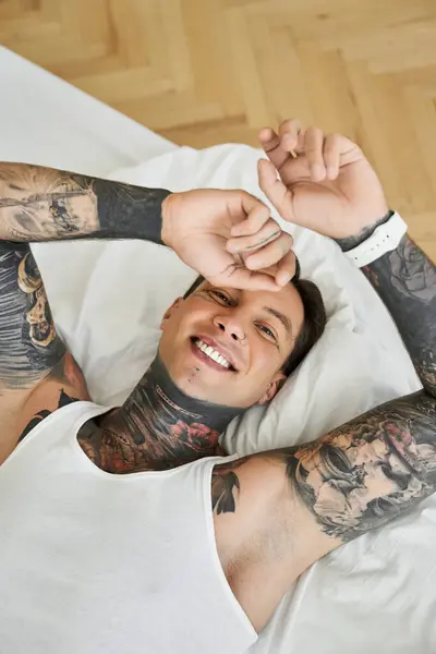The young man relaxes in bed, embracing his joyful personality. — Stock Photo