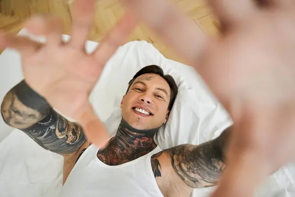 A handsome young man shares a cheerful moment at home, highlighting his detailed tattoos. — Stock Photo