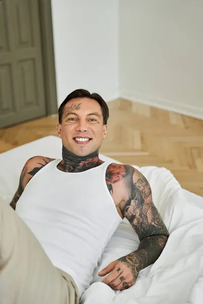 A young man smiles warmly, lounging comfortably in his home, embracing a relaxed moment. — Stock Photo