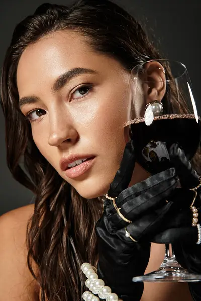 Uma mulher bonita em traje elegante goza de vinho tinto, apresentando sofisticação e charme. — Fotografia de Stock