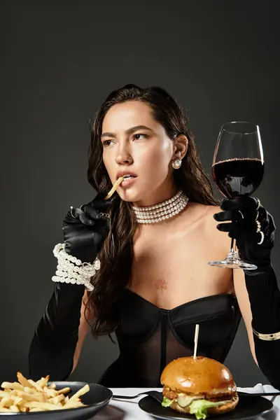 A stylish woman savors a glass of wine while tasting gourmet fast food delicacies. — Stock Photo