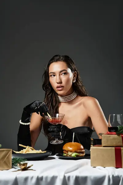 A young beautiful woman in an elegant outfit savors a cocktail while surrounded by gourmet food. — Stock Photo