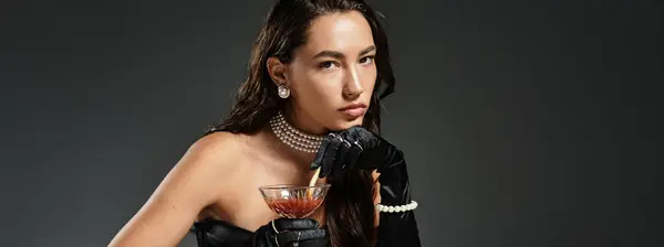 An elegant young woman with stunning attire savors a cocktail, exuding sophistication and style. — Stock Photo