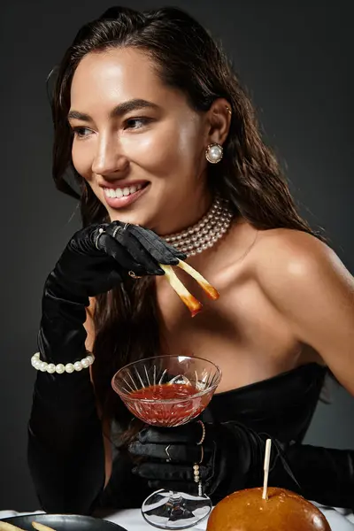 A young, beautiful woman in luxurious attire savors gourmet food and a cocktail while smiling. — Stock Photo
