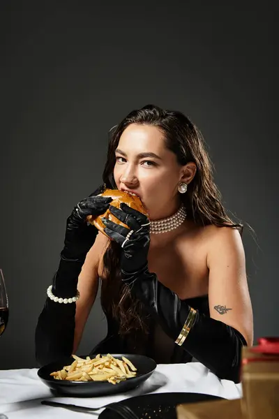A young woman in exquisite attire indulges in a gourmet burger and fries with elegance. — Stock Photo