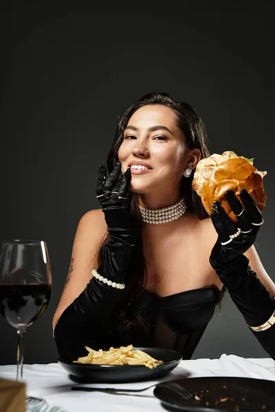 Uma jovem elegante desfruta de um hambúrguer gourmet com graça em um ambiente de jantar luxuoso. — Fotografia de Stock