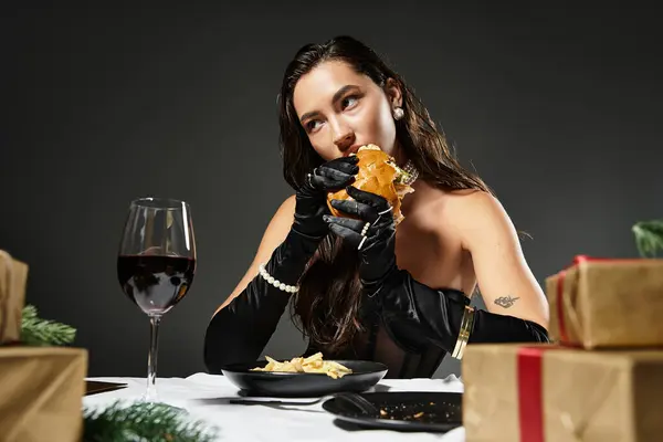 Eine stilvolle junge Frau genießt einen Gourmet-Burger an einem festlichen Tisch. — Stockfoto