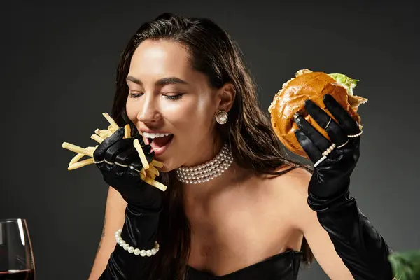 Eine schöne Frau in eleganter Kleidung gönnt sich einen Gourmet-Burger und knusprige Pommes. — Stockfoto