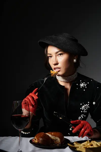 A young woman enjoys a gourmet meal, elegantly dressed and exuding sophistication in a dim setting. — Stock Photo