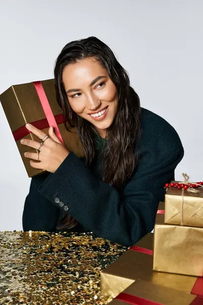 A joyful young woman holds delightful gifts in a festive setting. — Stock Photo