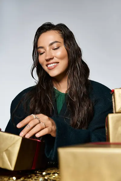 A beautifully dressed woman smiles as she wraps holiday gifts in a stylish environment. — Stock Photo