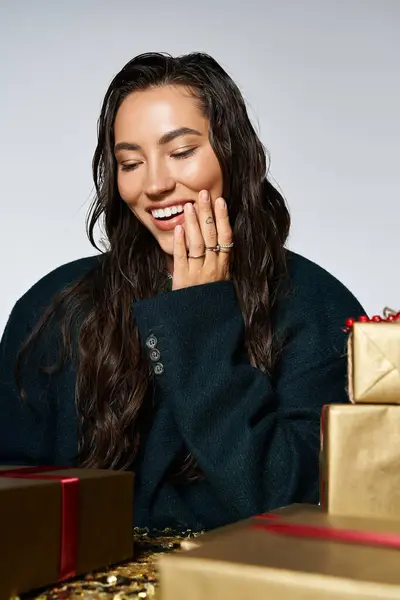 Eine strahlende junge Frau genießt einen Moment der Freude, umgeben von stilvoll verpackten Geschenken. — Stockfoto