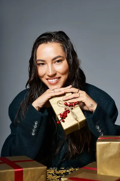 A sophisticated woman in stylish attire smiles playfully while surrounded by festive gifts. — Stock Photo