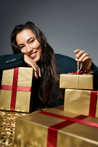 A stylish woman confidently smiles, showcasing beautifully wrapped gifts at a festive event. — Stock Photo