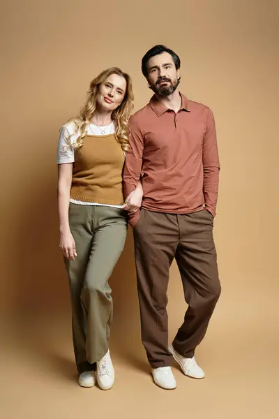 A happy middle aged couple smiles while standing side by side in trendy outfits, exuding warmth. — Stock Photo
