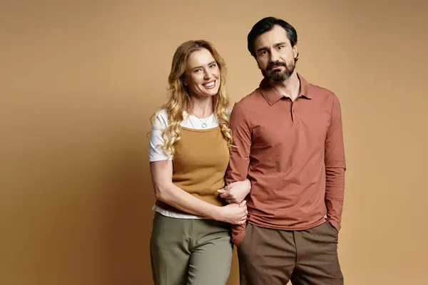 A middle aged couple stands close together, smiling happily in a charming studio setting. — Stock Photo