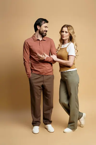 A middle aged couple smiles and chats closely while dressed casually. — Stock Photo
