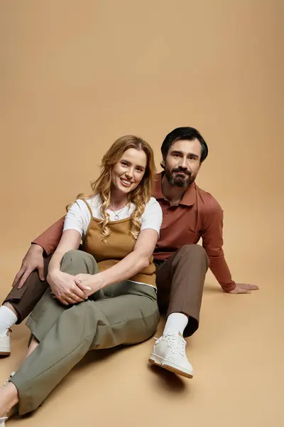 A joyful middle aged couple relaxes in stylish outfits against a soft backdrop. — Stock Photo