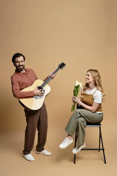 A middle aged man plays guitar while a cheerful woman holds flowers, enjoying the moment. — Stock Photo
