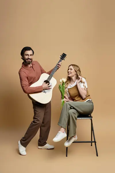 Um homem alegre toca guitarra como uma mulher sorri com flores frescas, espalhando alegria. — Fotografia de Stock