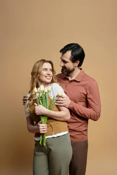 The couple smiles at each other, surrounded by fresh tulips in a cozy and intimate setting. — Stock Photo