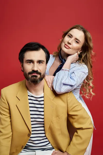A bearded man in a stylish jacket sits confidently as a woman playfully poses behind him. — Stock Photo