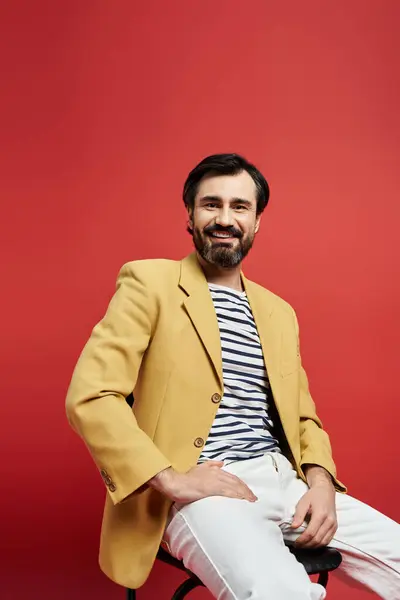 The man exudes charisma, seated comfortably, wearing a bright blazer and striped shirt. — Stock Photo