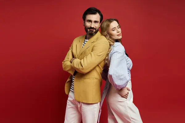 A middle aged couple stands back to back, blending styles and confidence in a vibrant setting. — Stock Photo
