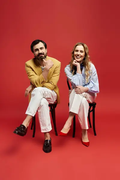 A middle aged couple sits comfortably on chairs, smiling and enjoying the moment. — Stock Photo