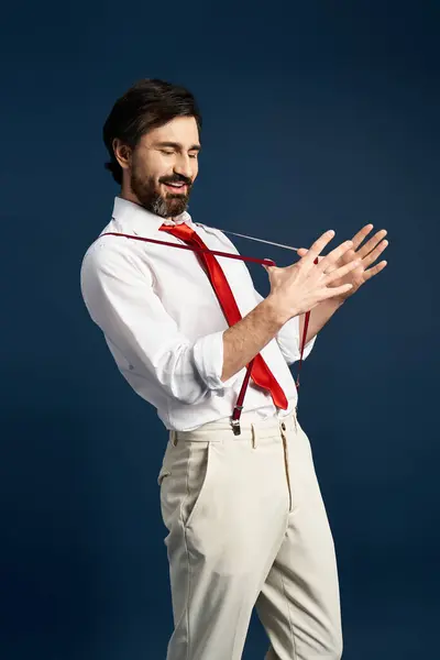A stylish man enjoys a playful moment while adjusting his tie with a playful grin. — Stock Photo