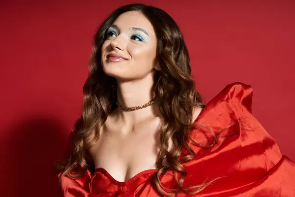 The young woman smiles warmly while dressed in a dazzling red gown, exuding confidence. — Stock Photo