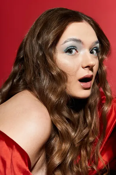 The young woman with long wavy hair shows a moment of surprise in a striking red outfit. — Stock Photo