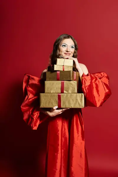 A cheerful young woman embraces a stack of elegant gifts, radiating happiness and festive spirit. — Stock Photo