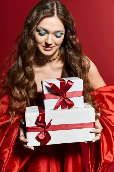 A beautiful young woman smiles as she holds two festive presents tied with red ribbons. — Stock Photo
