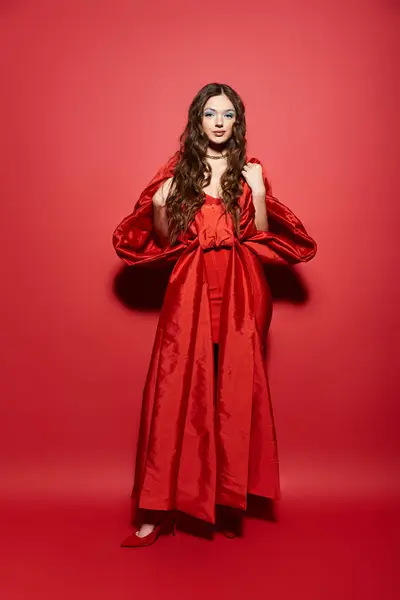 The elegant young woman in a bold red outfit stands confidently, showcasing her stylish flair. — Stock Photo