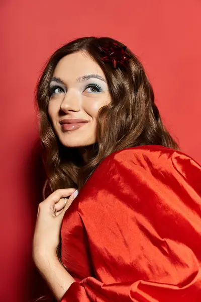 A joyful young woman smiles playfully in bold red fabric against a vibrant backdrop. — Stock Photo