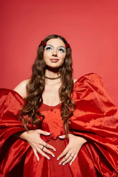 A stunning young woman showcases her elegance in a striking red dress with voluminous sleeves. — Stock Photo