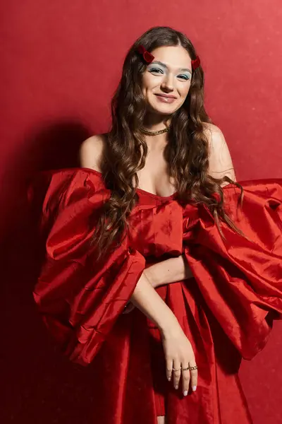Una hermosa joven se levanta con confianza en un traje rojo audaz, mostrando su encanto. - foto de stock