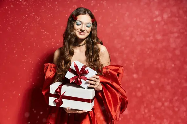 The young woman beams with happiness, showcasing her elegant red outfit and festive gifts. — Stock Photo