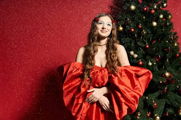 A festive young woman smiles warmly, surrounded by holiday decorations and falling snowflakes. — Stock Photo