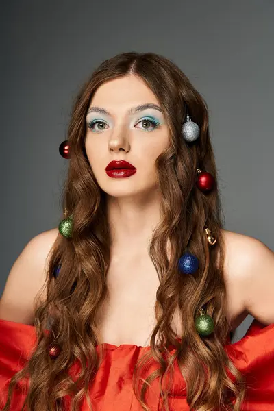A young woman showcases holiday spirit with colorful ornaments in her hair and a vibrant outfit. — Stock Photo