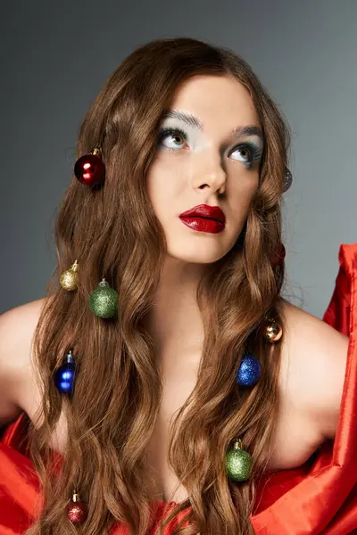 A young woman with long hair decorated by ornaments gazes upward, exuding festive elegance. — Stock Photo