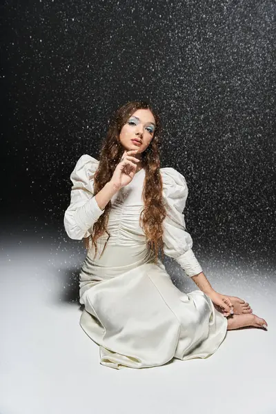 Uma jovem mulher com cabelo fluindo exala elegância enquanto se senta em meio a um pano de fundo macio e nevado. — Fotografia de Stock