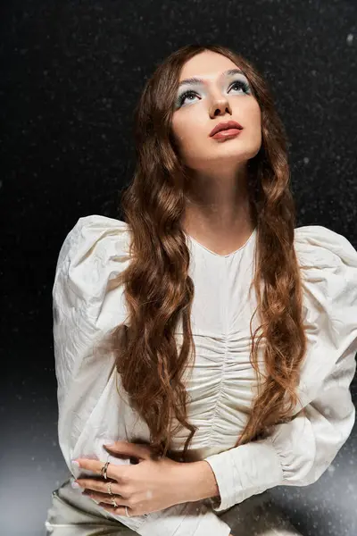 A young woman in white gazes thoughtfully upward in a serene setting. — Stock Photo