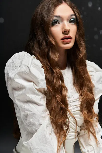 The young woman with flowing hair presents a captivating look, wearing a chic white blouse. — Stock Photo