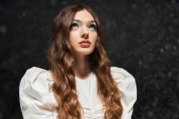 A adorável jovem mulher com cabelo fluindo olha pensativamente para o céu, iluminada suavemente. — Fotografia de Stock