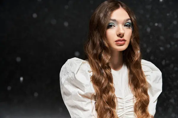 Uma jovem mulher posa graciosamente em um cenário mágico, destacando sua roupa elegante e cabelo ondulado. — Fotografia de Stock