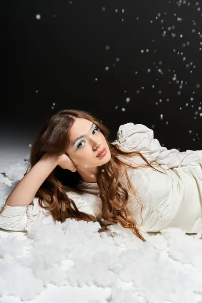 A young woman lies back in a dreamy setting surrounded by soft clouds and delicate snowfall. — Stock Photo